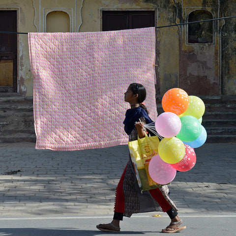 Molly Mahon's Quilt Peggy Pink hanging out to dry with girl walking past holding a handful of colourful balloons 