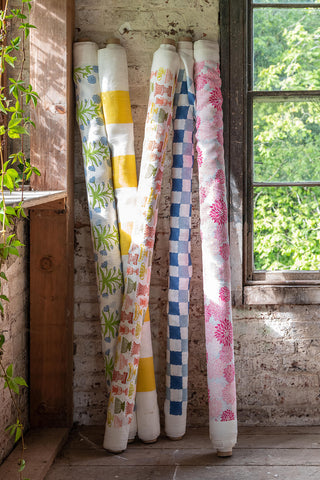 Rolls of colourful fabric leaning up against a warehouse wall next to a window from Molly Mahon's Bloom collection