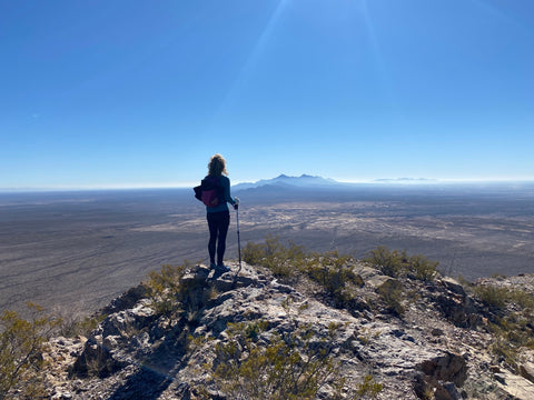 Woman standing alone on top of mountain, looking across a valley.