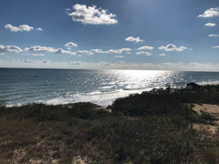 Clouds and sun shining over deep blue ocean with white capped waves at Cape Cod National Seashore