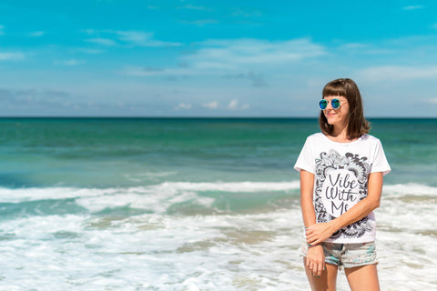 woman at a beach wearing sun glasses, travel skincare tips
