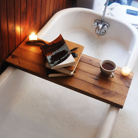 cozy bath tube with books and candle, practical bathroom hacks relaxation