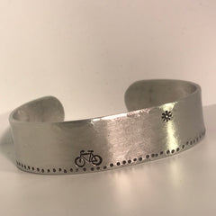 Hammered aluminum cuff bracelet featuring metal stamped bike ride on a sunny day.