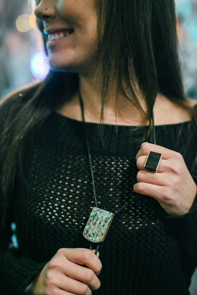 Woman wearing a Sticks & Stones Paua Select Abalone Bolo Tie and an Ebony Wood Ring