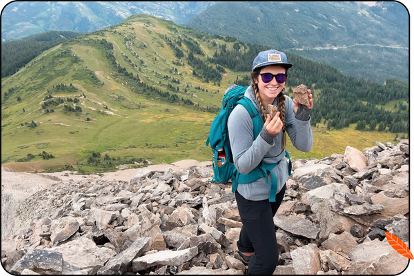 a backpacker poses for a photo with a mountainview backdrop