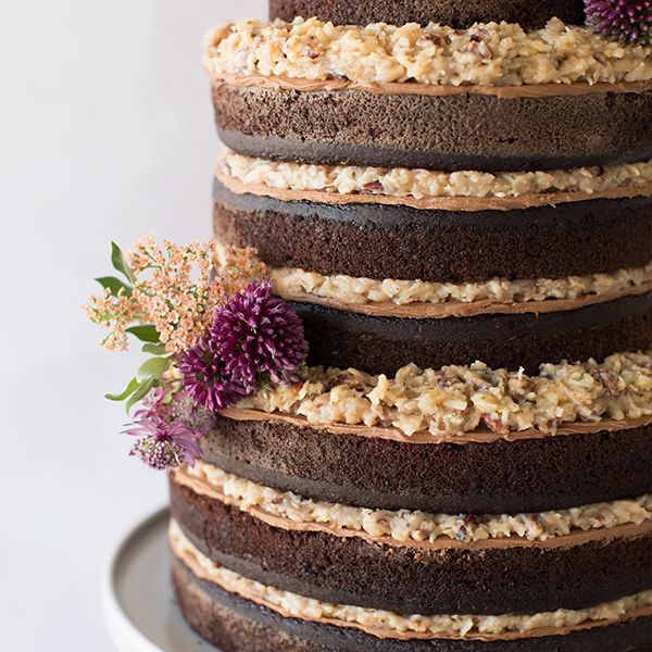 Three tier “naked” chocolate wedding cake. Chocolate cake filled with  chocolate ganache and chocolate buttercream then a light covering of fudge  icing on top. Fresh Red Roses, red grapes, raspberries, strawberries,  blueberries,