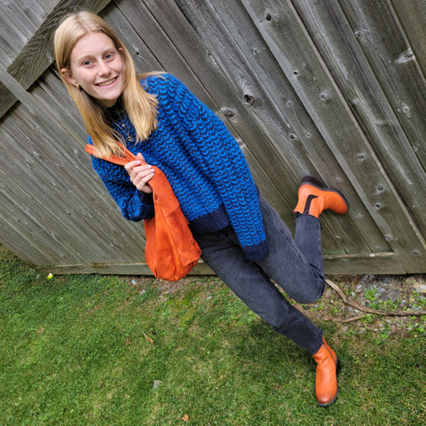 Kiera blue sweater pops next to her orange boots and accessories