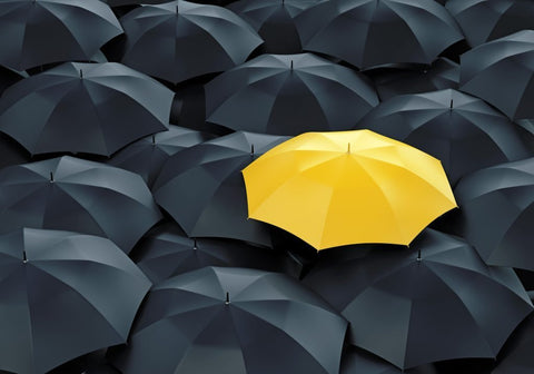 an image of a yellow umbrella surrounded by dark umbrellas