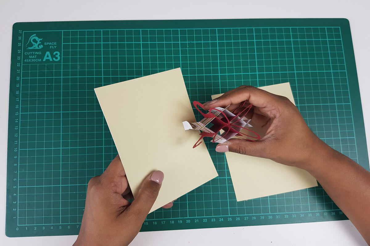 How To Make A Christmas Pop Up Card Tutorial - picture of slotting the tabs on the pop up present through the slits cut in the inner cover