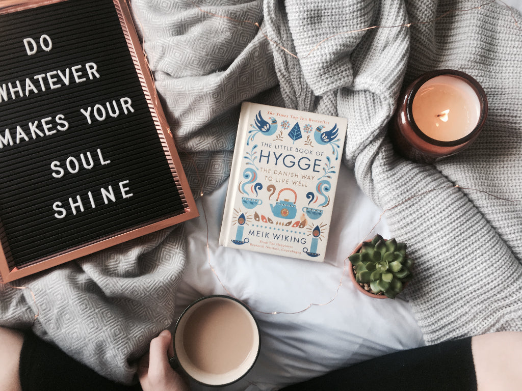 alt="the little book of hygge flatlay with candles and tea, bramble and fox collab with the slow living guide"