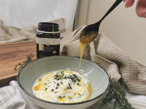 Bowl filled of Greek yogurt sprinkled with thyme, a hand drizzling honey on top