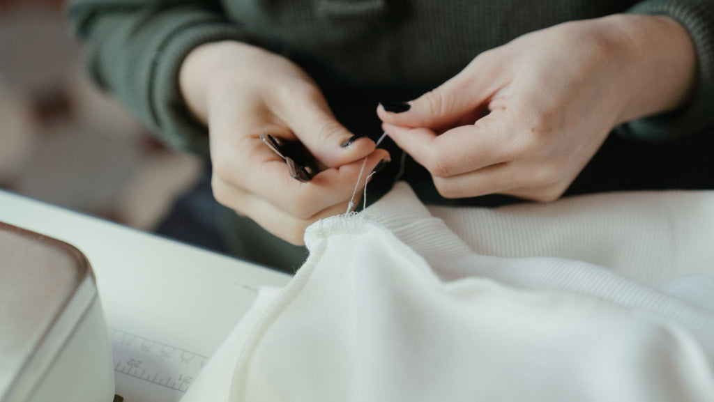 A person inserting a needle into a white sheet