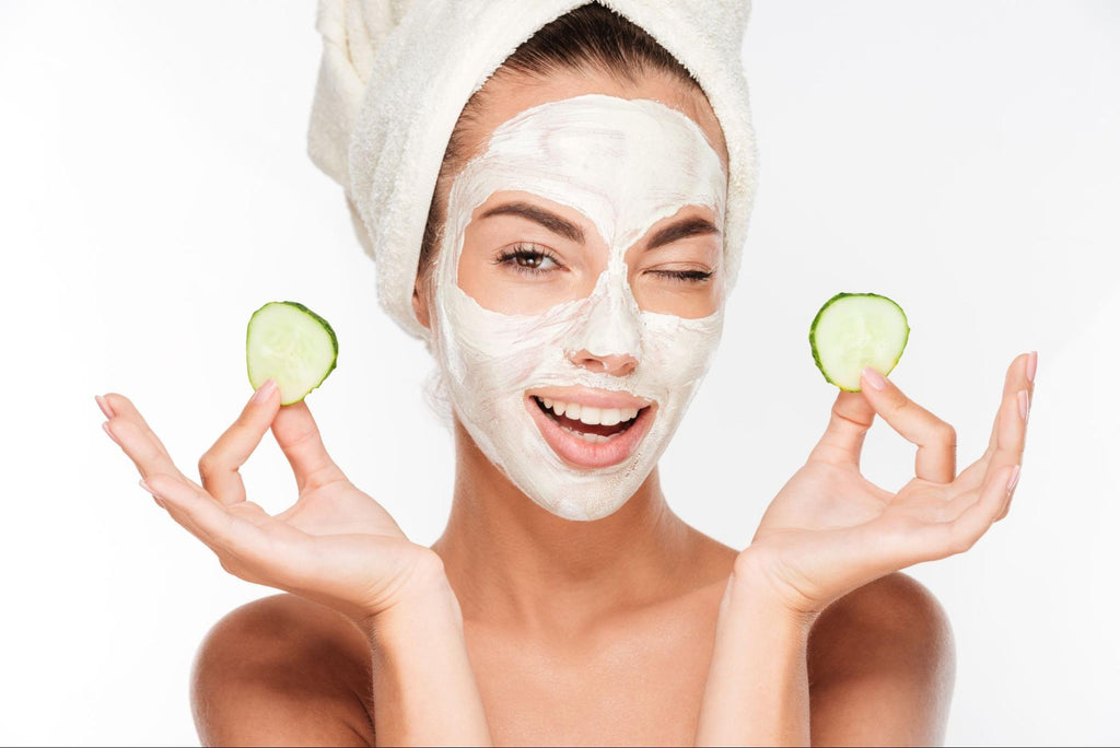 woman with facial mask holding cucumber