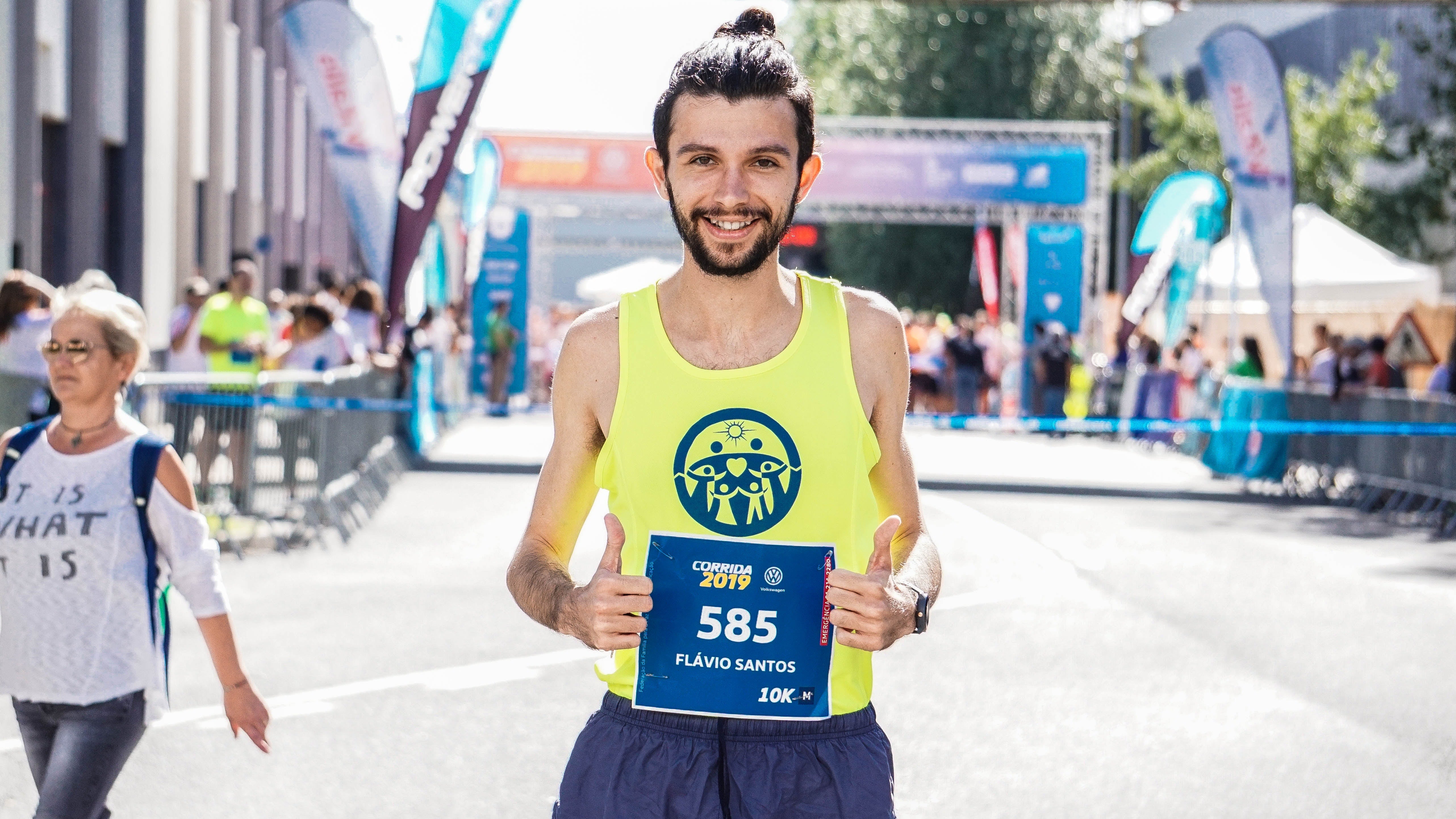 man wearing a yellow clothing is holding his number in a marathon