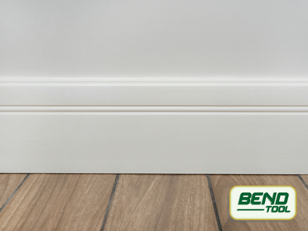 Bend Tool Co. - How to Paint Baseboards - Clean white profiled baseboard on white wall, wood tile.