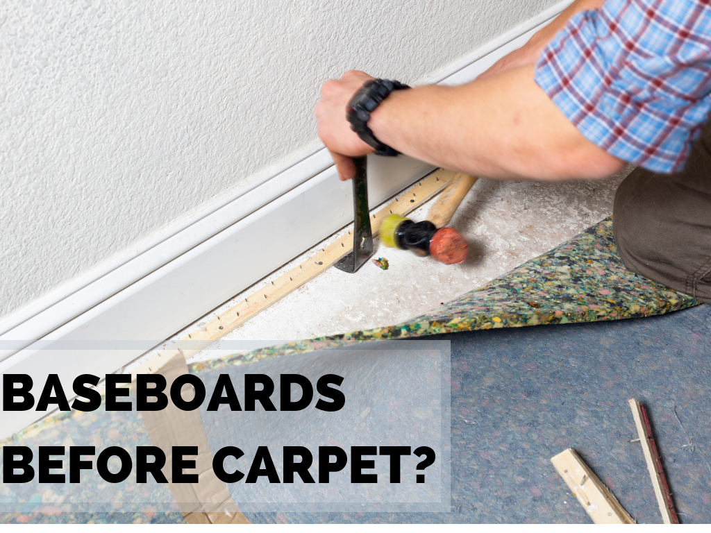 Baseboards before carpet? Carpet installer carefully removes tack strip against white baseboard with a claw hammer and small mallet.