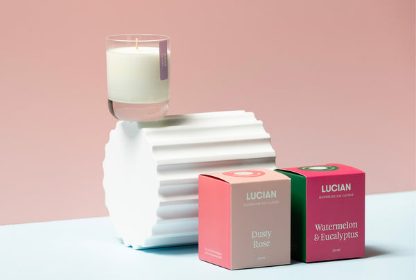 Bright Glass Australia-made Soy Candle Packaging sitting in front of a plinth with a pink backdrop