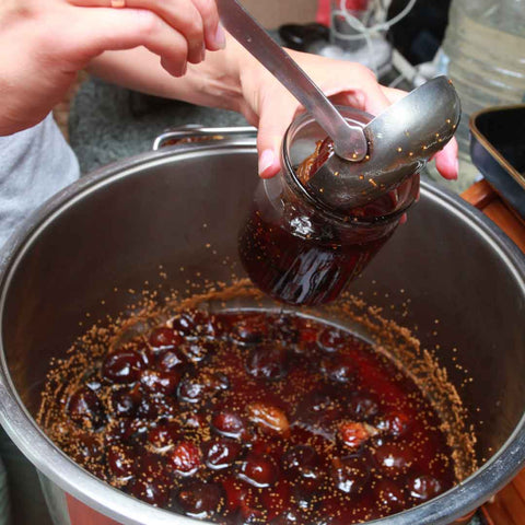 Pouring homemade fruit jam into jar