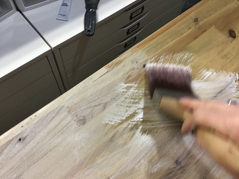 person using a paint brush to apply a white wash solution over stain