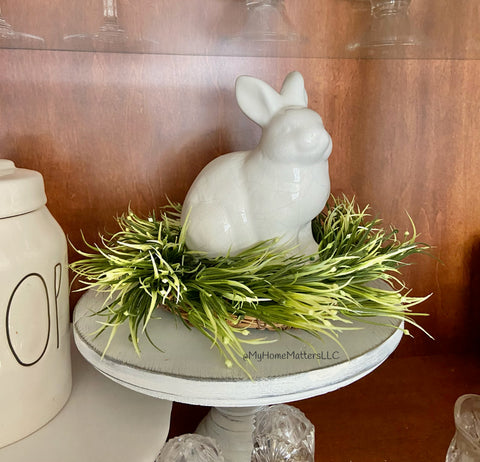 white bunny sitting on greens on a white cakestand