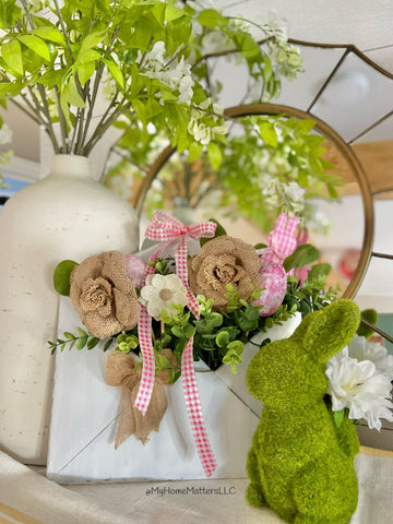 Spring decor on a table using greens and flowers and bunnies