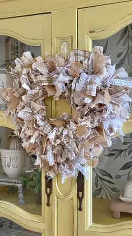 yellow hutch with heart shaped rag wreath hanging over the doors