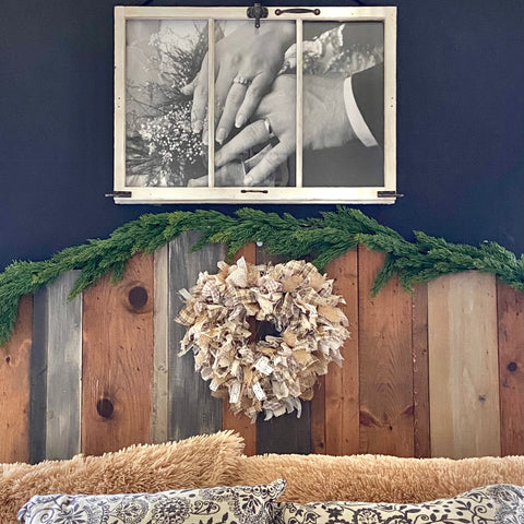 neutral colored rag wreath hung on a planked wooden headboard against a black wall