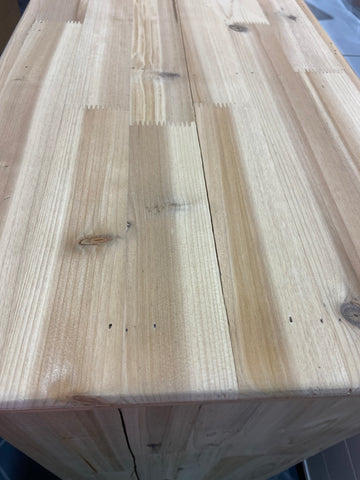 cabinet top that has been sanded down to raw wood showing close up of large crack/gap down the center