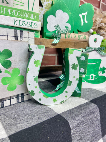 wooden horse shoe decoupaged with white paper that has shamrocks on it