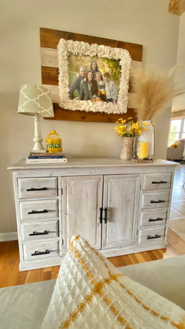 full on view of a refinished white washed cabinet with black hardware and pops of yellow accents on top