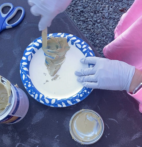 person with latex gloves mixing up a solution of Bondo on a paper plate