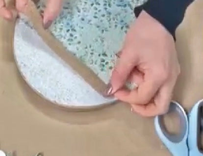 close up of someone applying burlap ribbon across a flat wooden egg