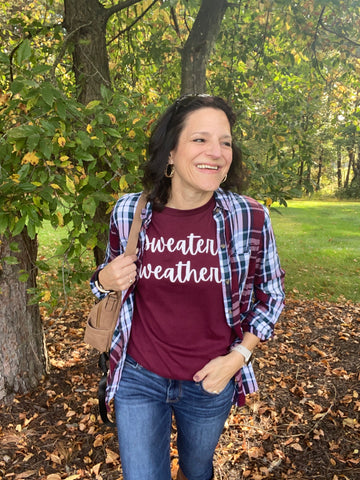 woman wearing navy and maroon tshirt and flannel; tshirt says "sweater weather"