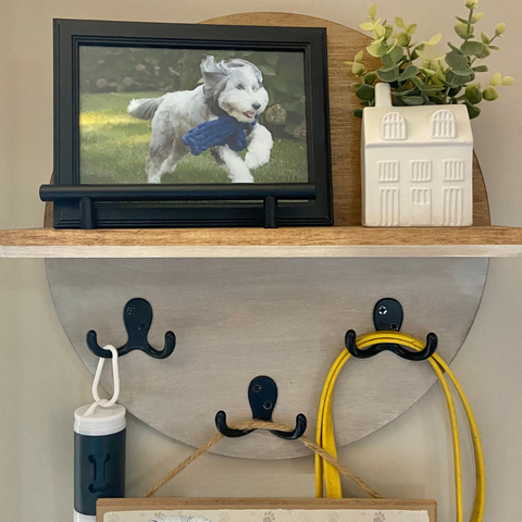 round wall shelf styled with photo of a dog in a black frame and dog leash hanging from hooks on the sign