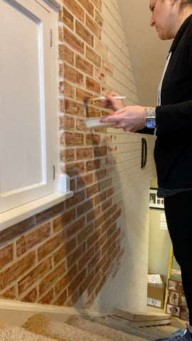 person painting faux brick on a stairwell wall