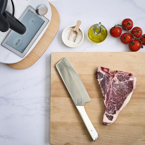 Cleaver knife on wooden chopping board with steak and Thermomix