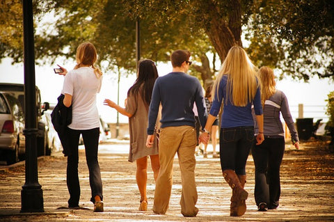 group of friends walking outside a man and woman are holding hands photo is taken from behind