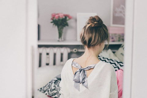 Young girl wearing a sweater in a room photo taken from behind