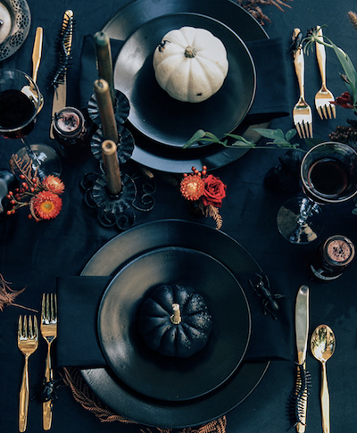 2 black place settings with white and black pumpkins and gold silverware