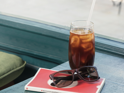 Cold Brew Tea in a Tall Glass with ice - a book and a pair of sun-glasses