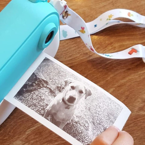 kid instant print camera printing a black and white dog picture