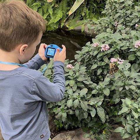 a grandson taking a picture of a flower outdoors using the littlelens camera