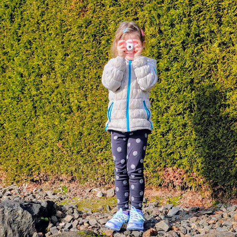 a young girl holding a little lens camera