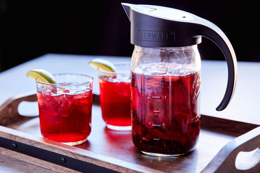 a mason jar and two cups sit on a tray with sun tea brewed with the craft cold brew filter