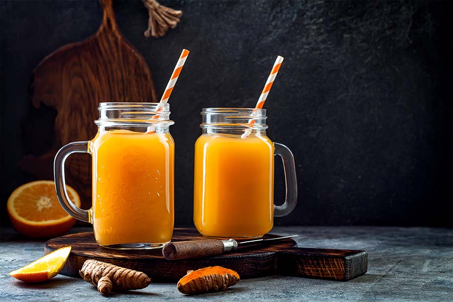 two jars filled with mocktails sit on a cutting board with mocktail ingredients surrounding them