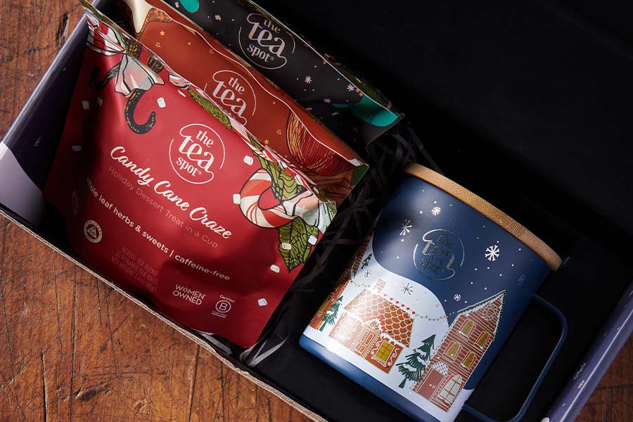 a tea gift set is open with three bags of tea and a holiday themed mug