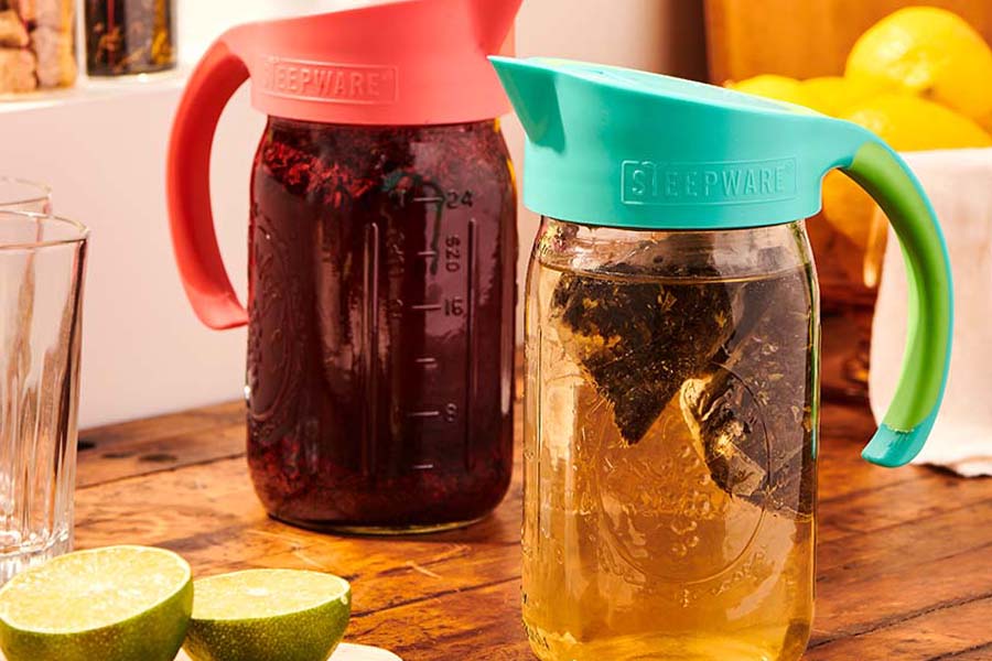 tea mason jars with tea bags and brewed iced tea in them sit on a table