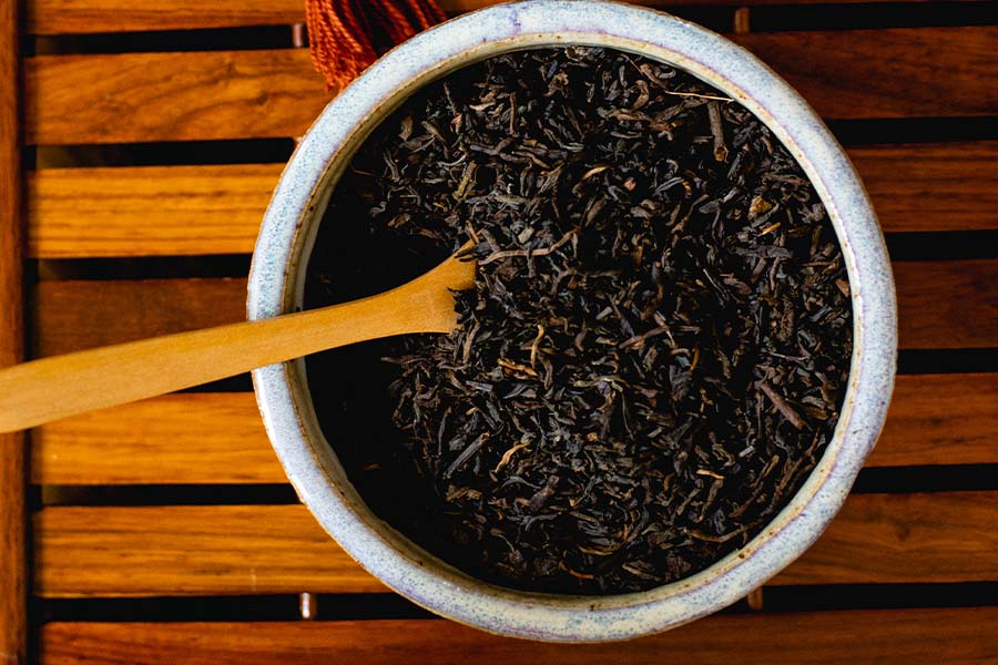 a bowl of loose leaf tea sits on a wooden table 