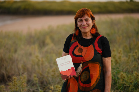 Ali Cobby Eckermann holding her book by the ocean at sunset