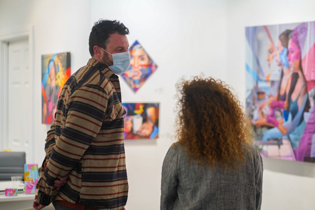 Photograph of two people talking during Ian Robertson-Salt's "Nine to Five" spotlight exhibition Opening Reception of New Contemporary paintings at Voss Gallery in San Francisco, January 2022.